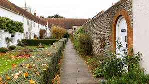 A narrow stone pathway flanked by white buildings and a brick wall with a door labeled "Cottage Gate". - Canon Gate , Chichester Cathedral  - sleeps 4 guests  in 2 bedrooms (Chichester)
