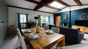 A dining area with a wooden table set for four, a sofa, and a television in the background. - Canon Gate , Chichester Cathedral  - sleeps 4 guests  in 2 bedrooms (Chichester)