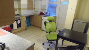 A compact kitchen with a washing machine, a dining table, and a chair. - Light and Airy 1 bed Flat With Large Basement Kitchen and Private Outside Area (leeds)