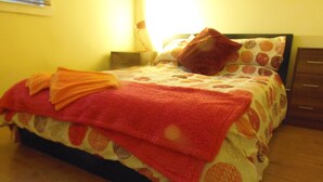 A bed with a patterned bedspread, a red blanket, and a pillow. - Light and Airy 1 bed Flat With Large Basement Kitchen and Private Outside Area (leeds)