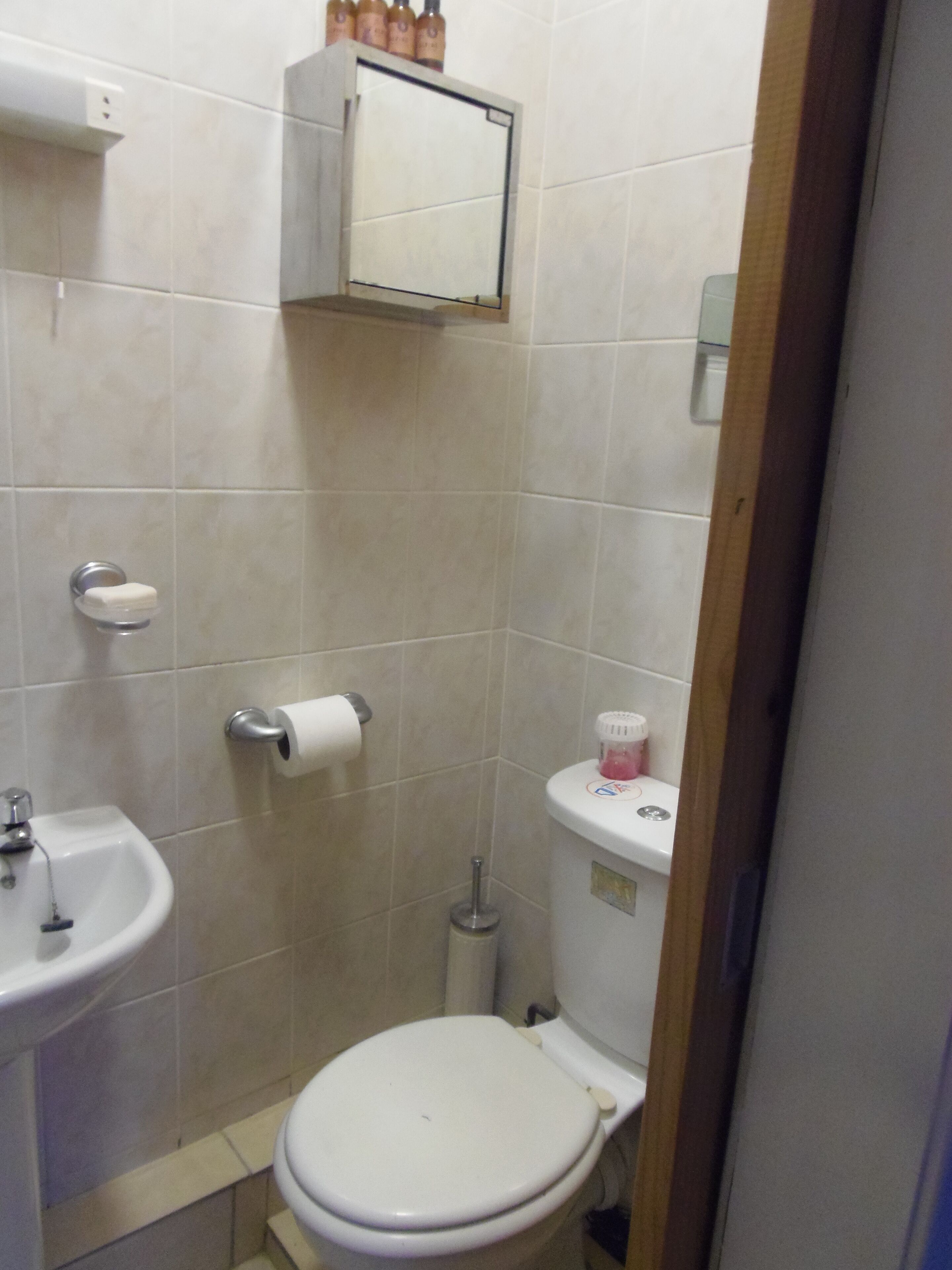 Une petite salle de bain avec des toilettes, un lavabo et un meuble au-dessus du miroir.