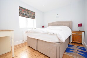 A bedroom with a bed, bedside tables, a window with a curtain, a radiator, and a rug.