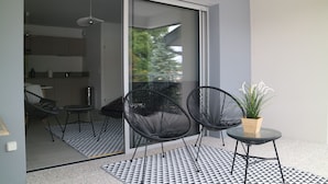 Un balcón moderno con dos sillas negras, una mesita y una planta en maceta.