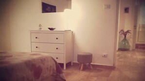 Um quarto com uma cama, penteadeira, espelho e um banquinho.