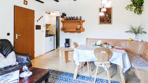 Ein gemütliches Wohnzimmer mit Essbereich, Holzmöbeln und einer Küche im Hintergrund.