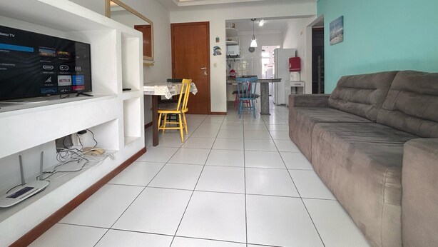 A modern living room with a flat-screen TV, a brown sofa, and a dining area with a table and chairs. - 222, apartment in a gated community with a shared swimming pool. (Bombas)
