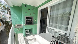 A balcony with a white table and chairs, a small sink, and a window with a view of the outside. - 222, apartment in a gated community with a shared swimming pool. (Bombas)