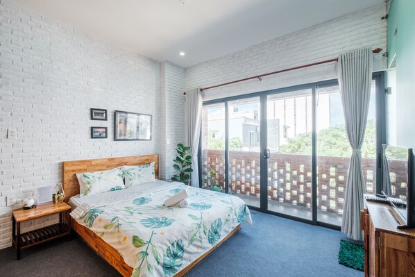 Relax in a spacious bedroom with a large bed, sliding glass door to an outdoor area, and a minimalist design.