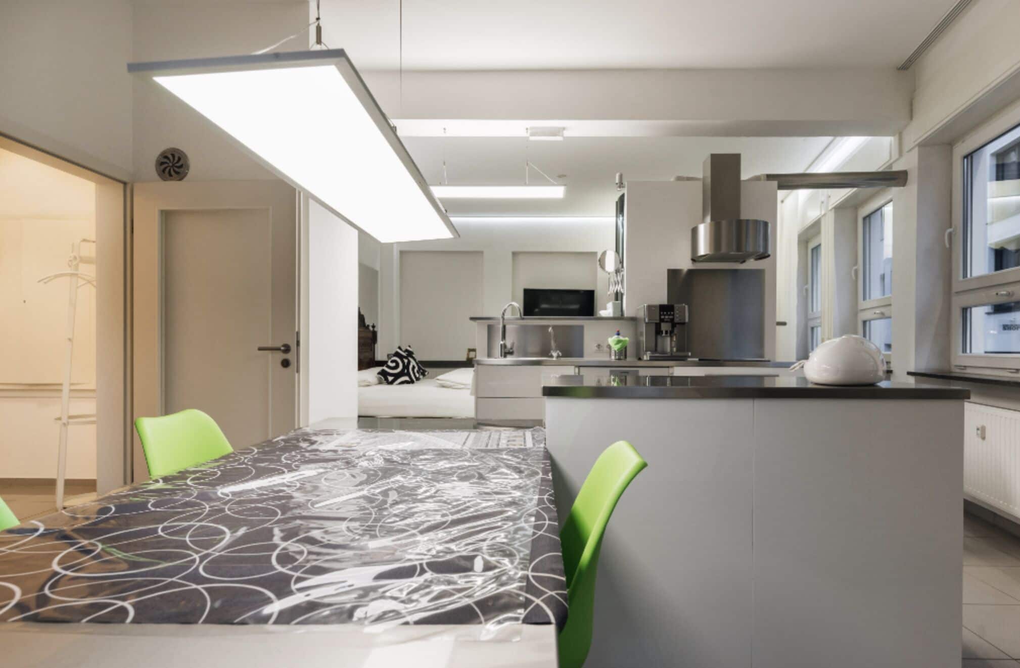 Uma cozinha moderna com uma ilha central, uma área de refeições com toalha de mesa estampada e vista para a sala de estar.