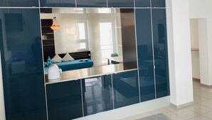 Un salon moderne avec un mur d’accent recouvert de carreaux bleu foncé, un canapé avec des coussins bleus, une table basse blanche et un luminaire suspendu.