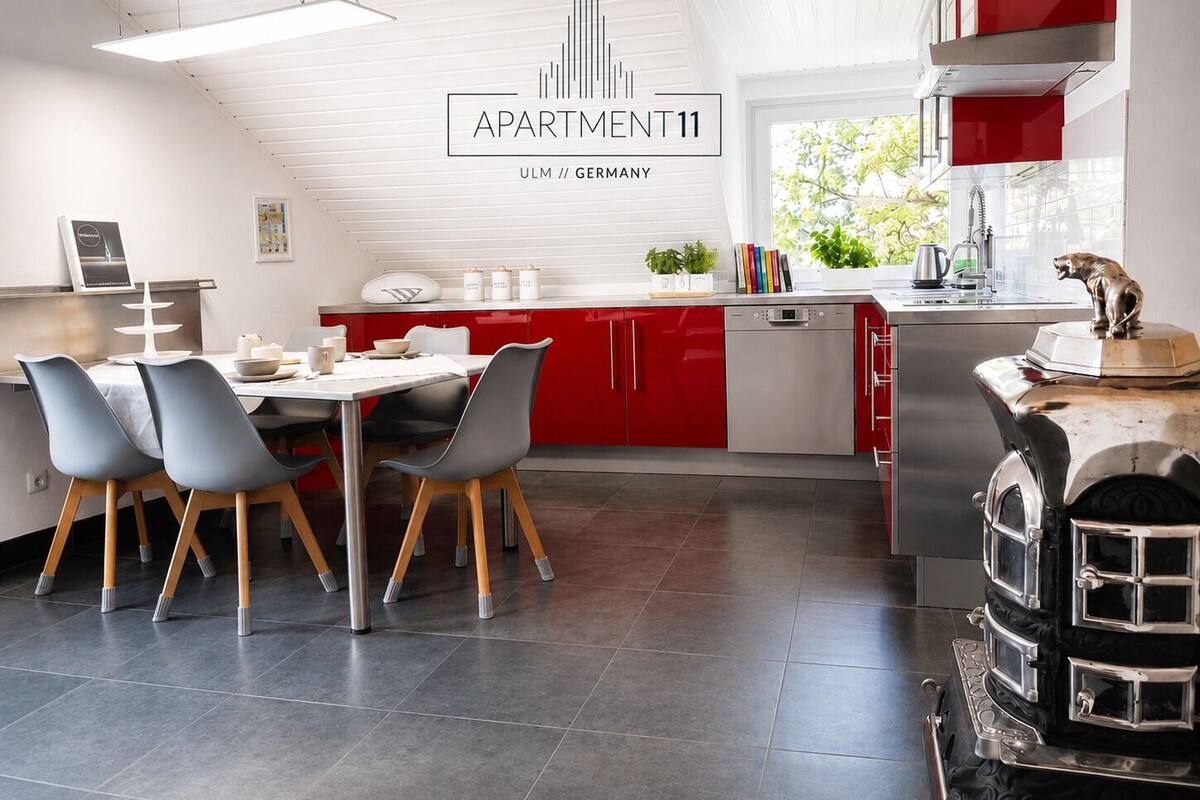 Una cocina moderna con gabinetes rojos, un comedor con sillas grises y una isla de cocina.