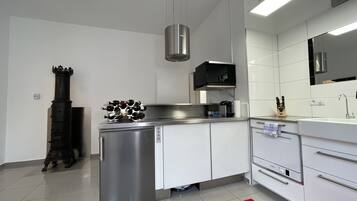 A modern kitchen with stainless steel appliances, white cabinetry, and a red rug.