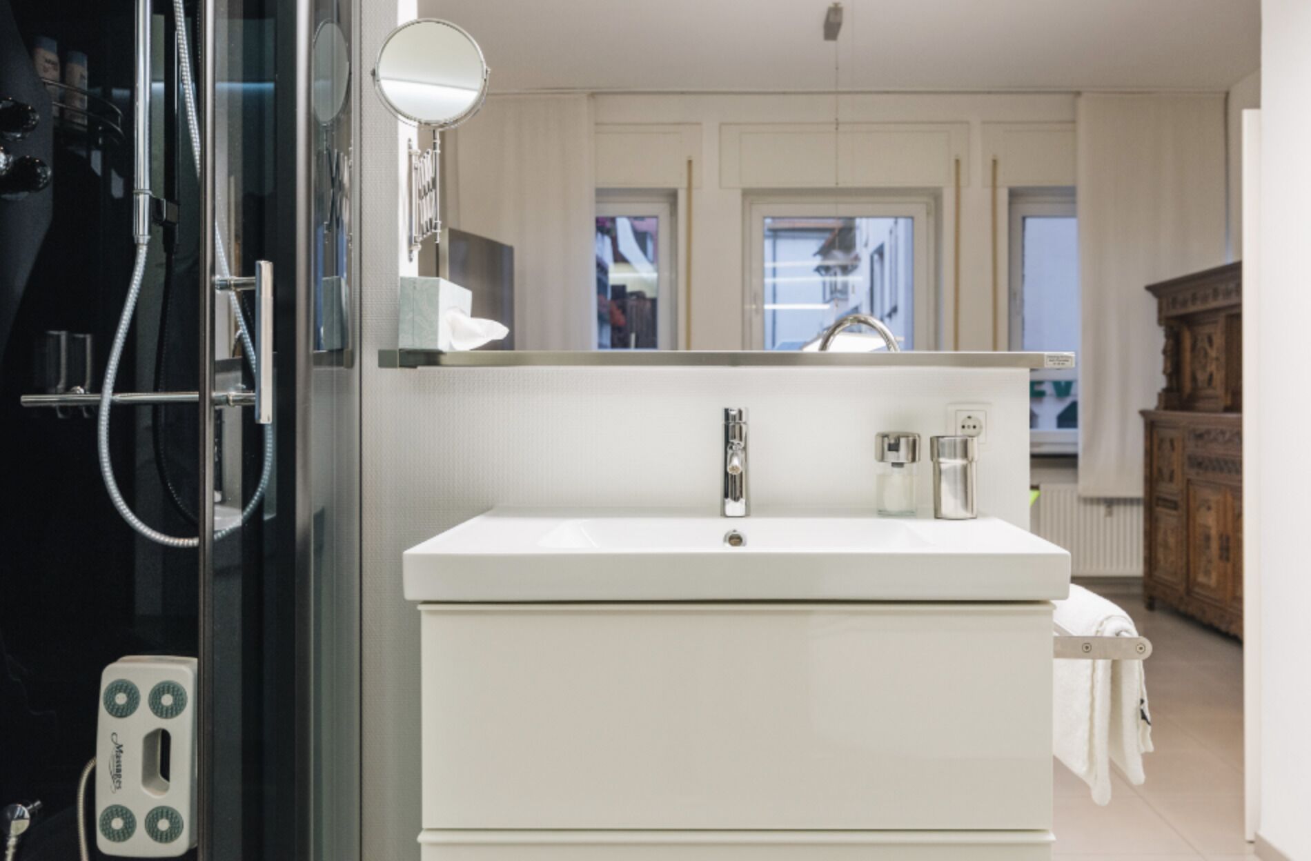 A modern bathroom with a white sink, a mirror, and a shower area.