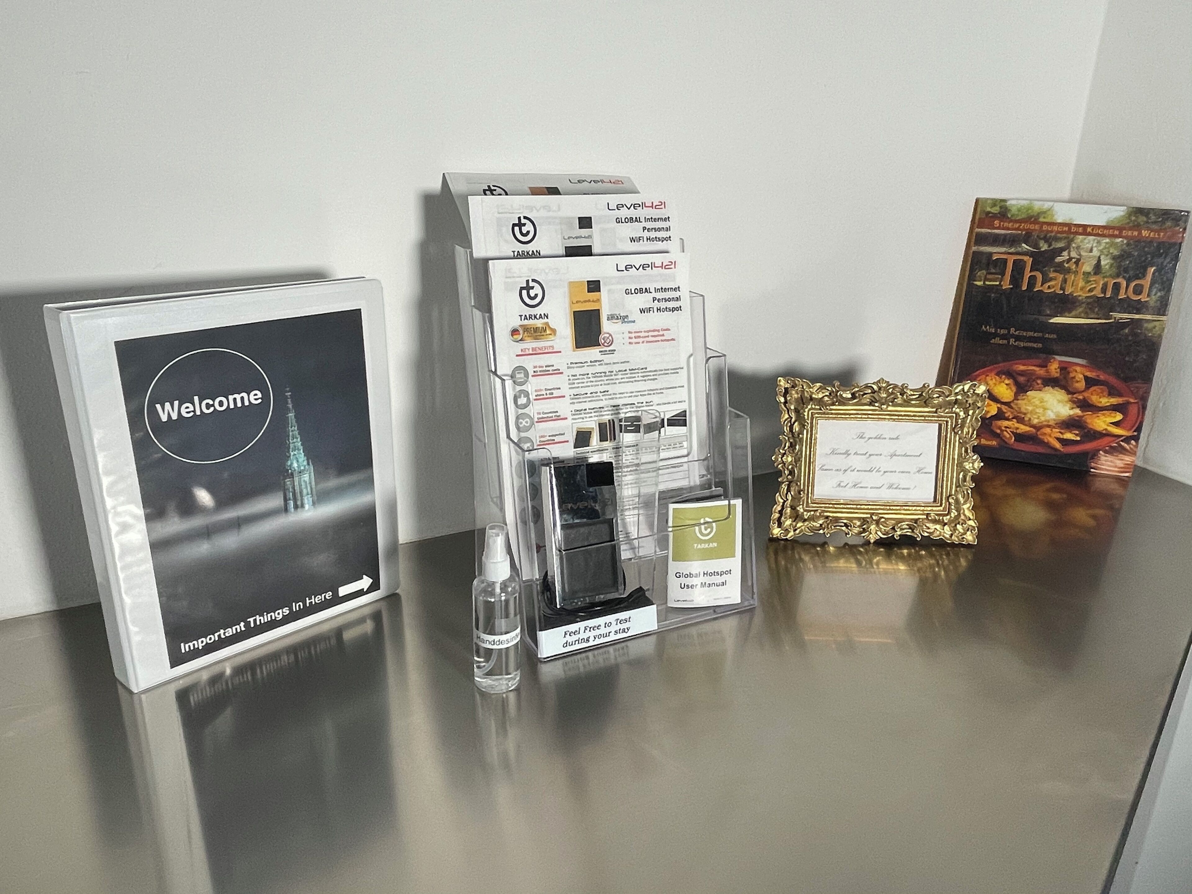 A display of Tarkan Global Internet Personal WiFi Hotspot products, a welcome sign, a framed note, and a book titled 'Thailand'.