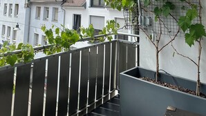 Un balcon donnant sur un immeuble doté d’un toit en pente et de nombreuses fenêtres.