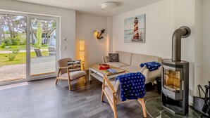 Tunnelmallinen olohuone, jossa on sohva, nojatuoleja, pöytä, takka ja maalaus majakasta.