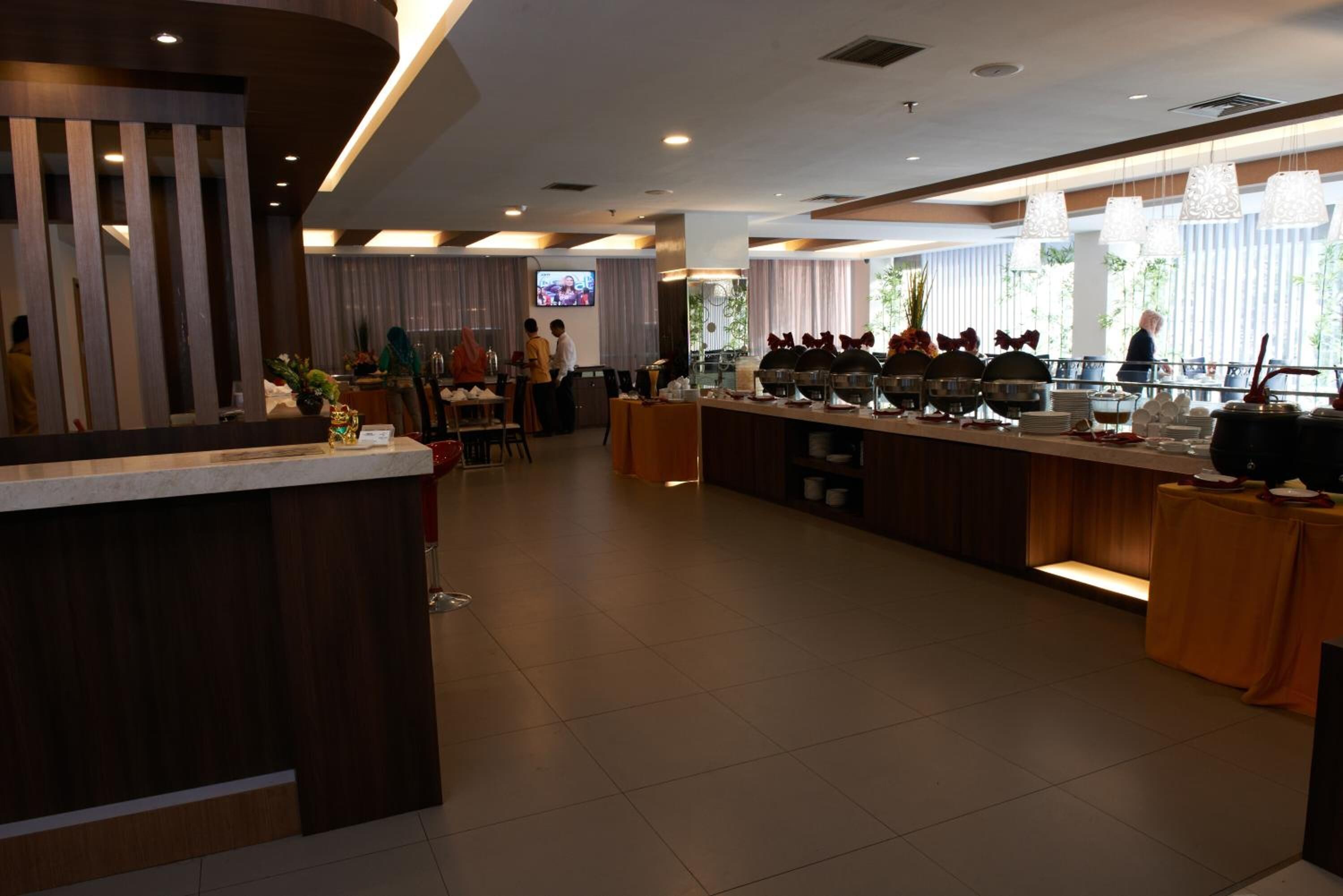 A modern hotel lobby with a reception desk, buffet area, and seating.