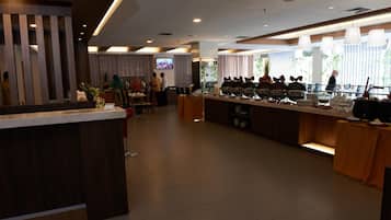 A modern hotel lobby with a reception desk, buffet area, and seating.