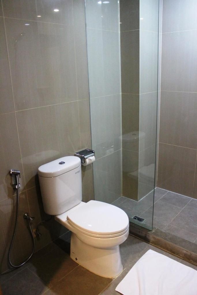 Une salle de bain moderne avec des toilettes, une douche en verre et une serviette blanche sur le sol.