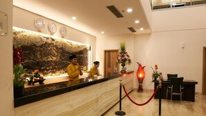 A hotel reception area with a marble counter, clocks, a red rope barrier, and a desk with chairs. - Winstar Hotel (Pekanbaru)