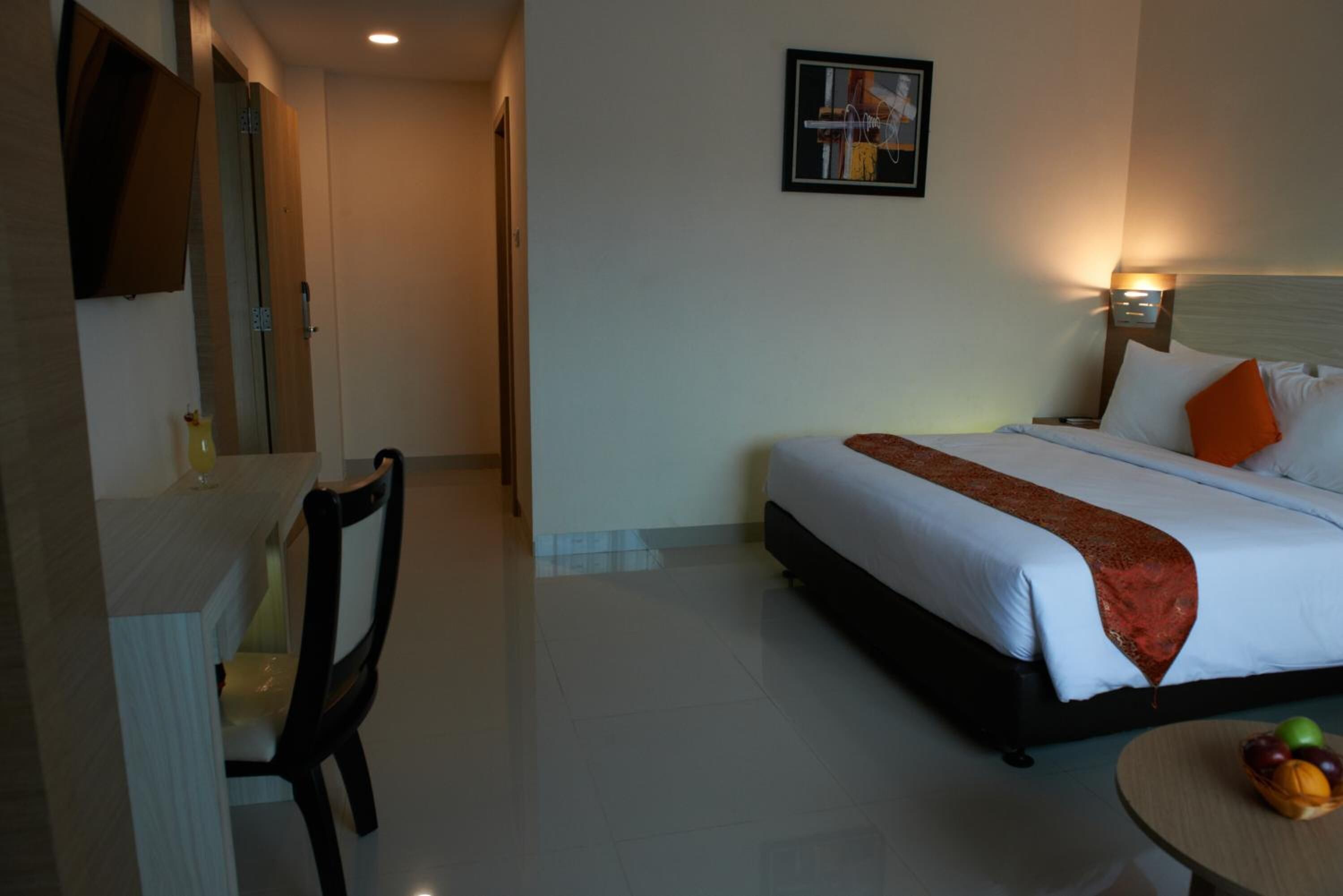 A hotel room with a bed, a desk, and a chair.