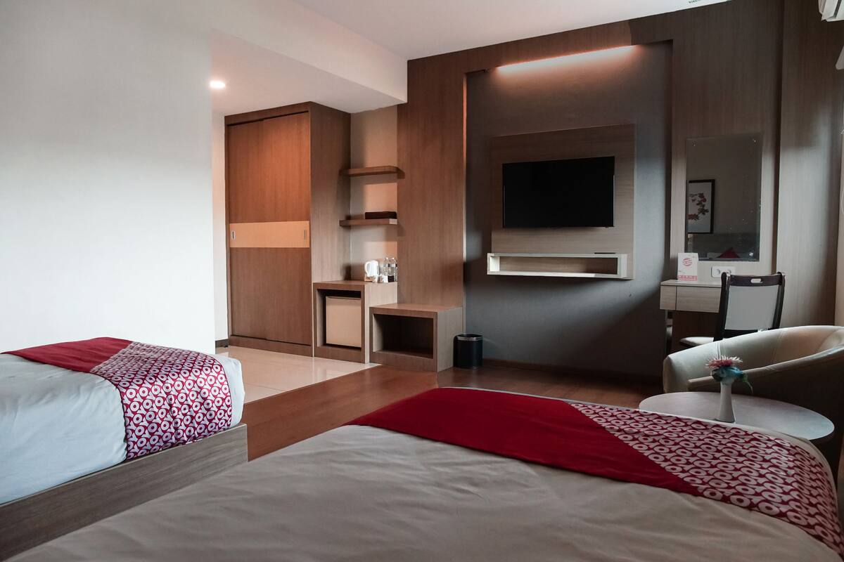 Une chambre d’hôtel avec deux lits, un bureau, une chaise, une télévision et un miroir.