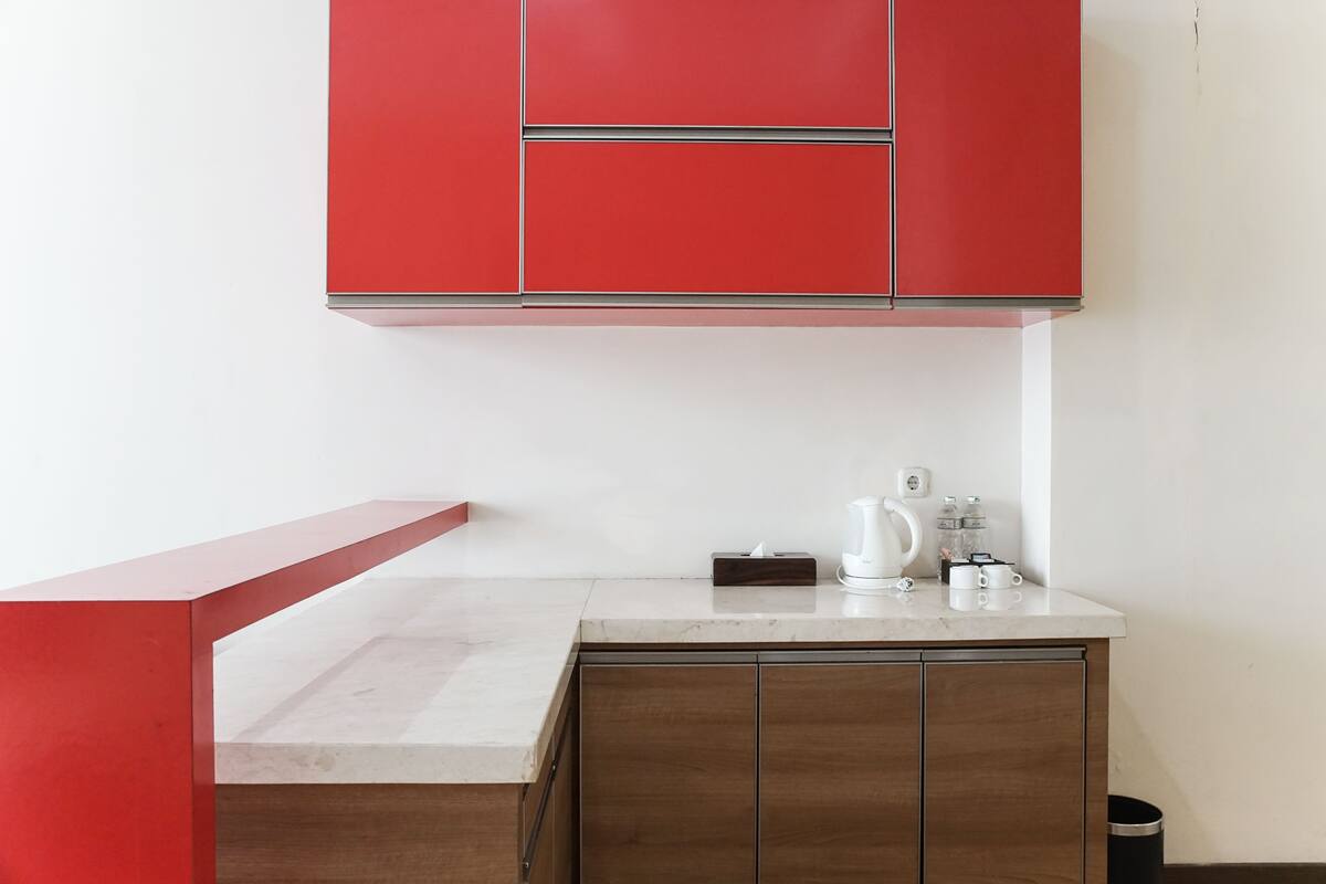 Une cuisine avec des meubles de rangement rouges, un plan de travail en marbre et un meuble en bois en dessous.