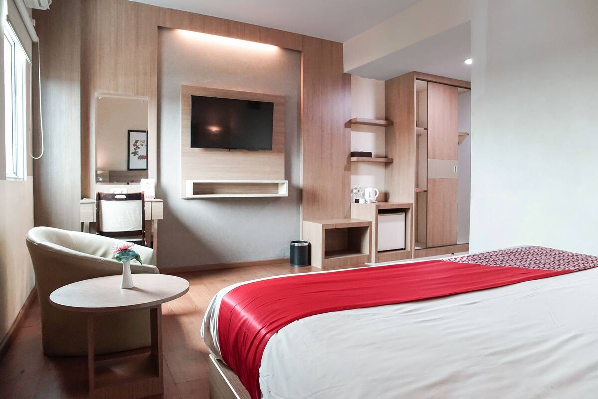 Une chambre d’hôtel comprenant un lit, un téléviseur fixé au mur, une chaise, une petite table et une armoire.