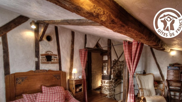 Une chambre à coucher rustique avec un lit en bois, un mur en pierre et une poutre en bois au plafond.