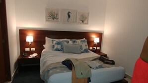 Et hotelværelse med en stor seng, to sengeborde med lamper, en loftventilator og billedkunst på væggen.