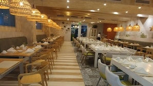 En restaurant med lange borde og stole, varm belysning og gulvfliser med mønster.