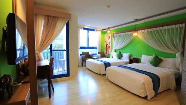 Habitación de hotel con dos camas, un balcón, un escritorio y una silla.