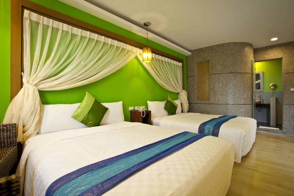 A hotel room with two beds, green walls, and a shower area.