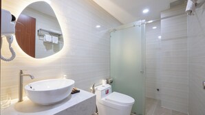 A modern bathroom with a large oval sink, a toilet, and a glass-enclosed shower. - SAZI AMILA Nguyen Hue HOTEL - Free Banh Mi (Ho Chi Minh City)