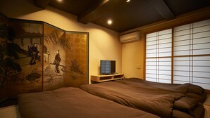 Une pièce de style japonais traditionnel, avec un sol recouvert de tatamis, un paravent shoji et une œuvre d’art accrochée au mur.