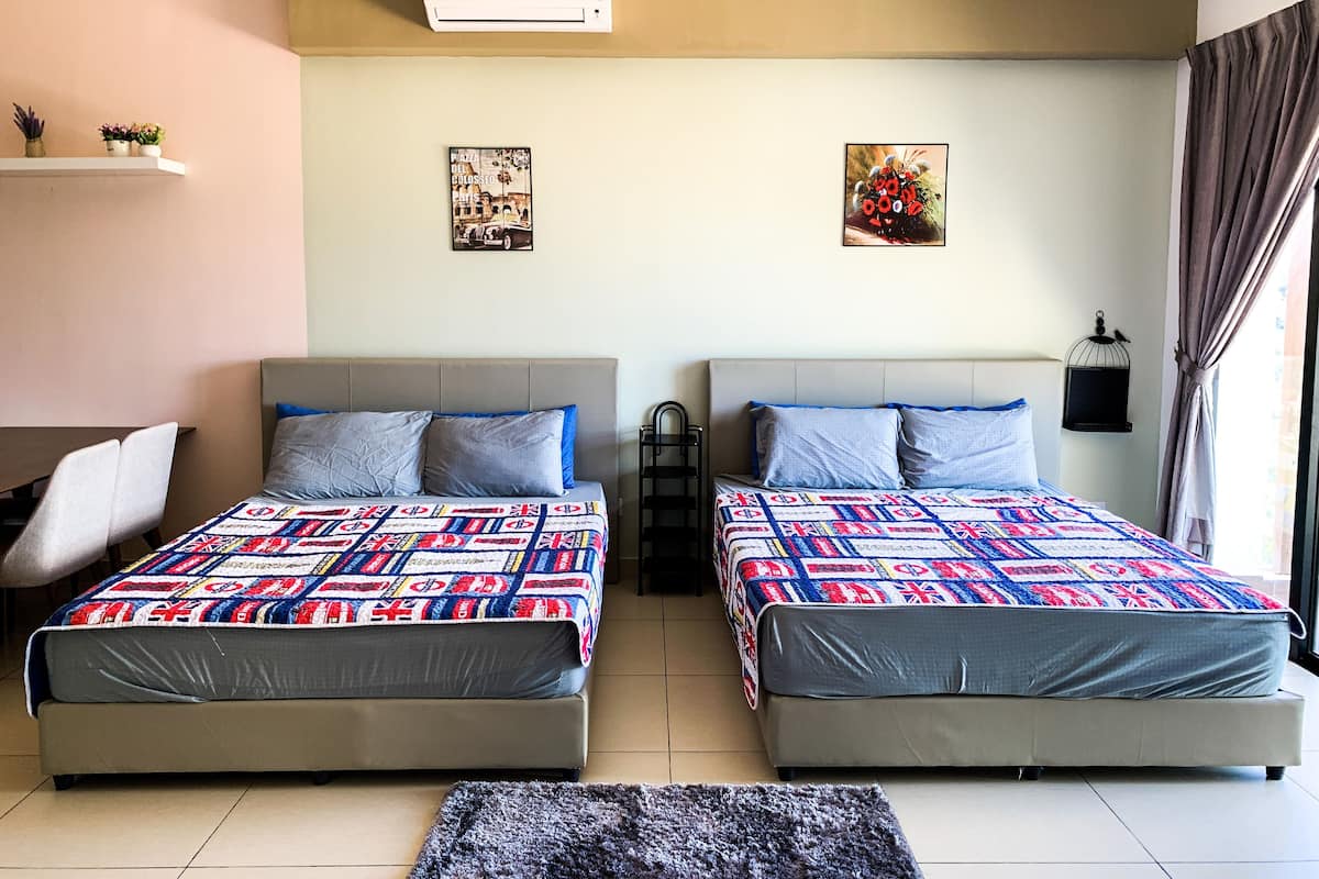 A double room with two beds, each with a patterned quilt, a small shelf with decorative items, and a wall-mounted air conditioner.