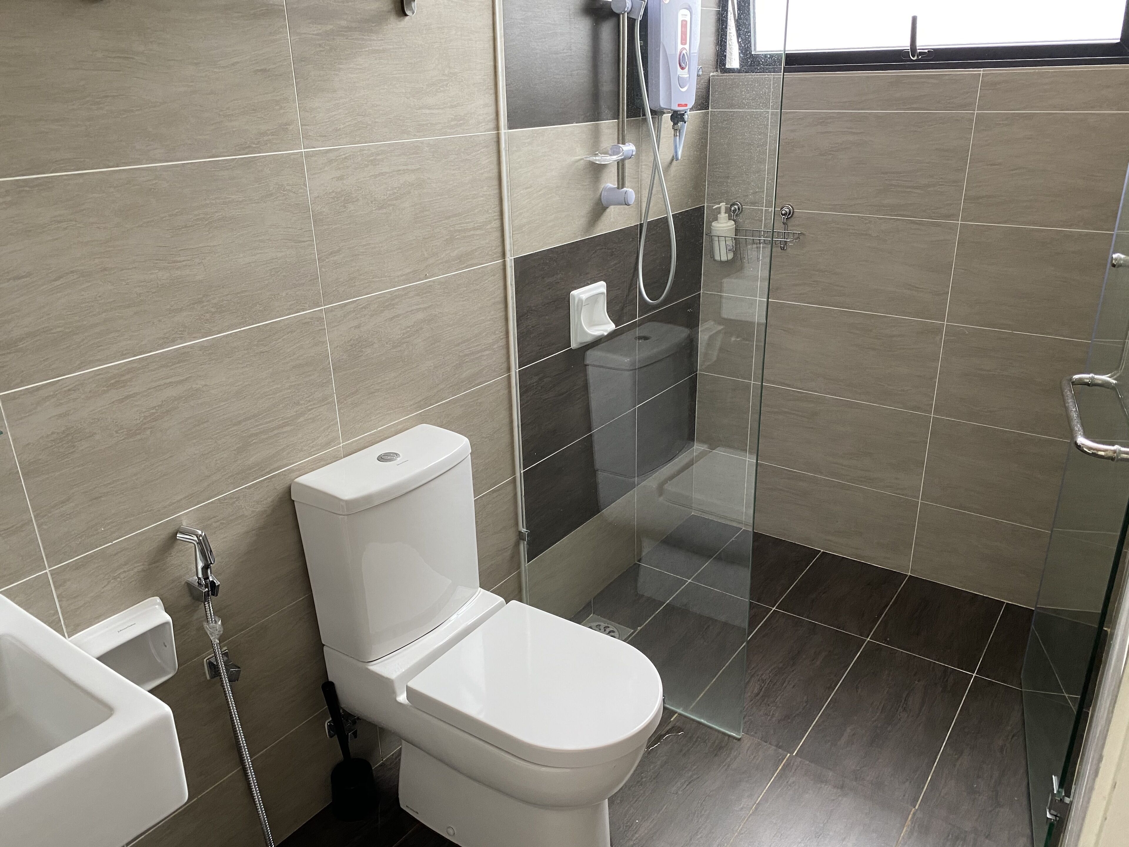 A modern bathroom with a toilet, a shower, and a glass-enclosed shower area.