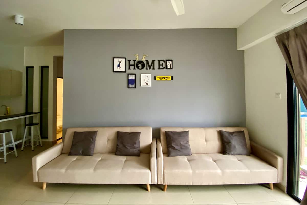 A modern living room with two sofas, a ceiling fan, and a wall with framed pictures and a 'HOME' sign.