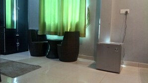 Een moderne kamer met een klein tafeltje, twee stoelen, een kast en een stopcontact aan de muur.