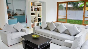 A modern living room with a sofa set, a coffee table, and a bookshelf. - Ricco Tara (Boossa)