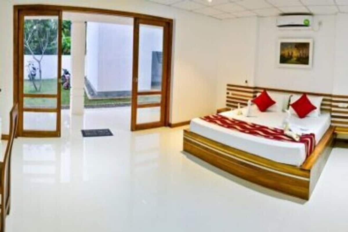 A bedroom with a large bed, a sliding glass door leading to a balcony, and a framed picture on the wall.
