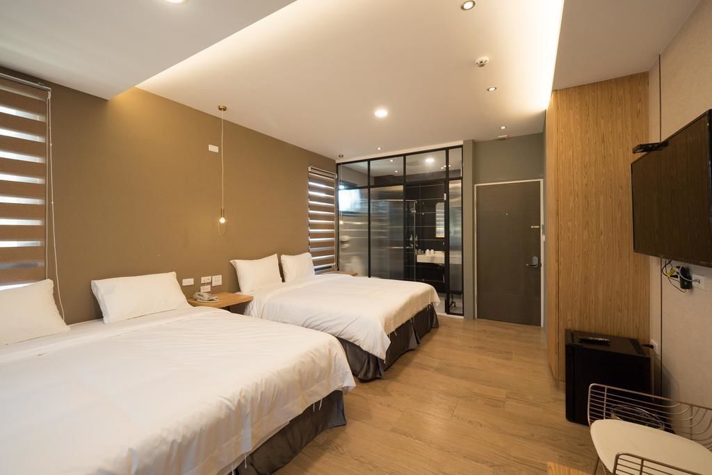 A modern hotel room with two beds, a walk-in closet, a shower, and a TV mounted on the wall.
