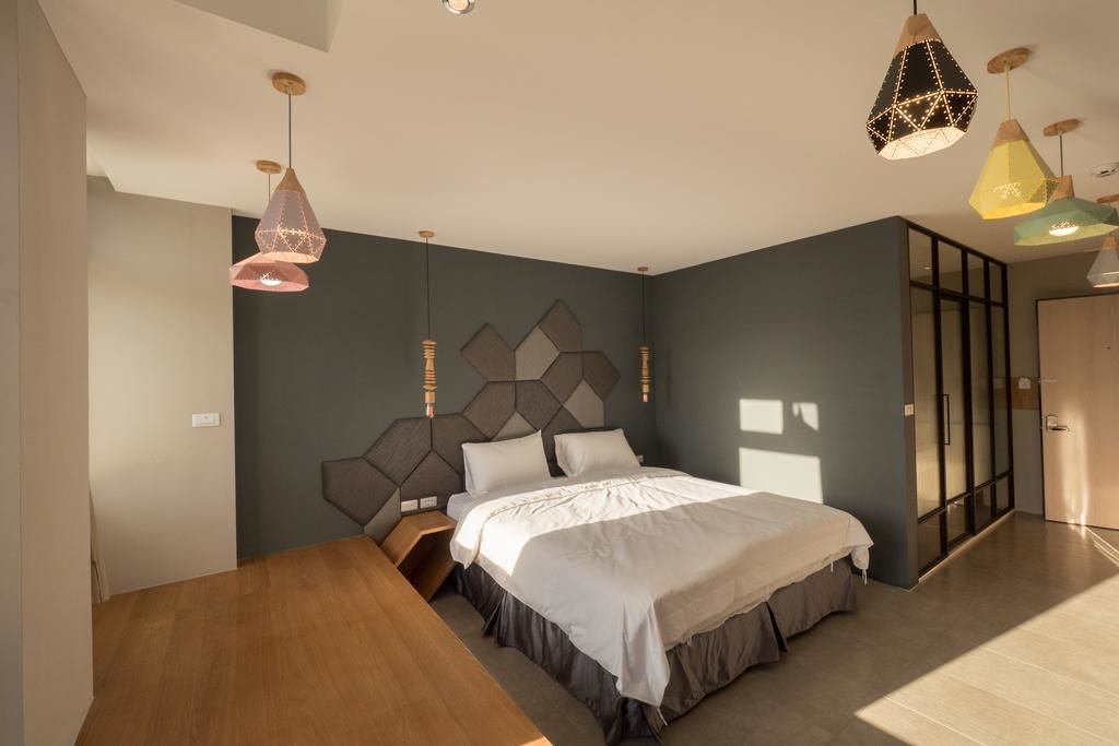 A modern bedroom with a bed, bedside tables, and a wooden desk.