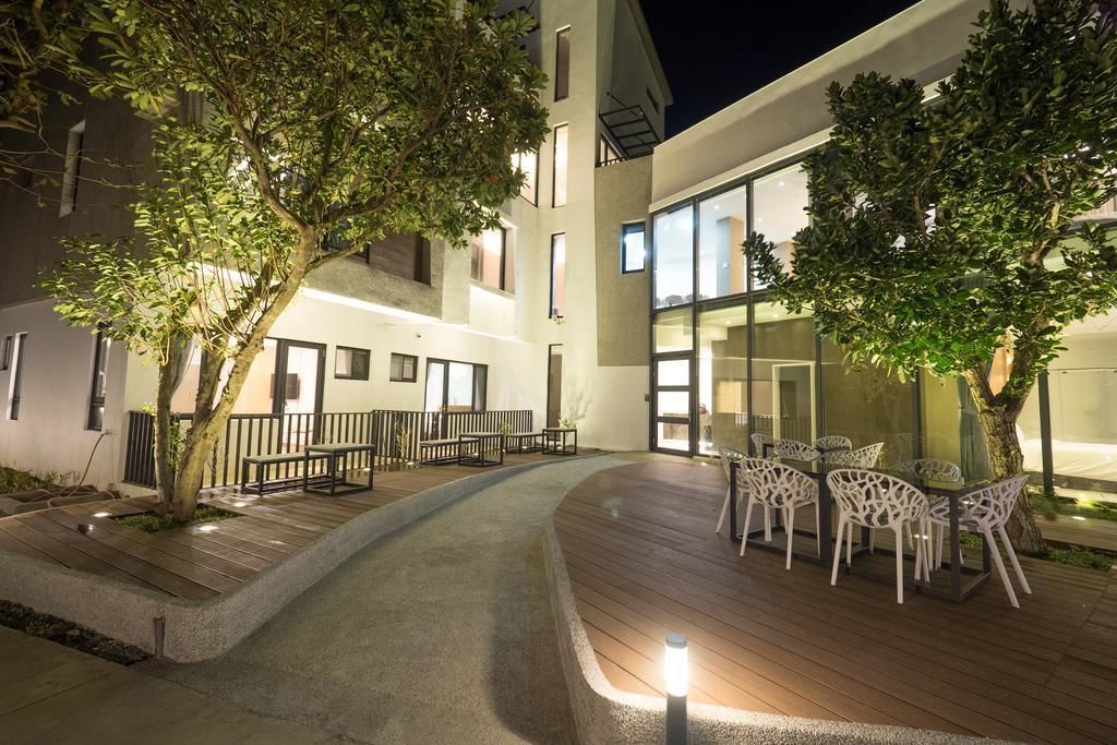 An outdoor patio area with wooden flooring, white chairs, and a table.