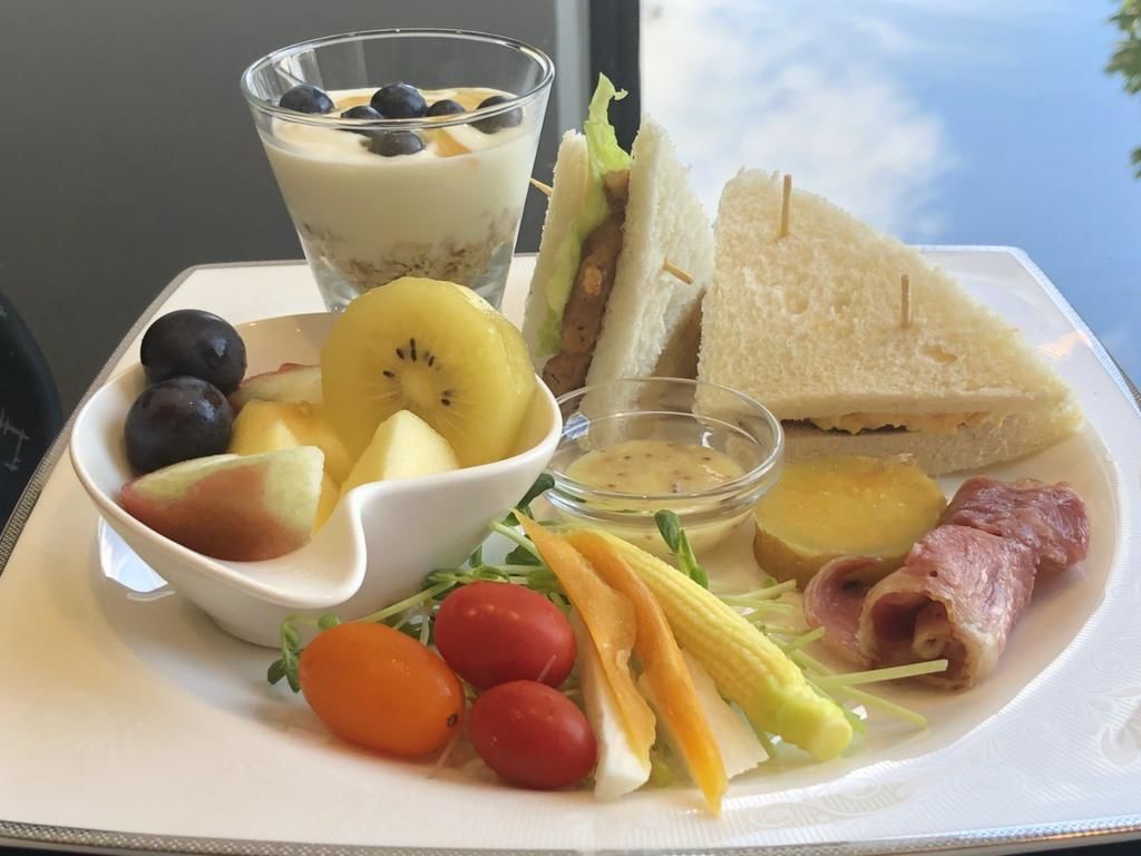 A meal tray with a sandwich, fruit, salad, and a dessert.