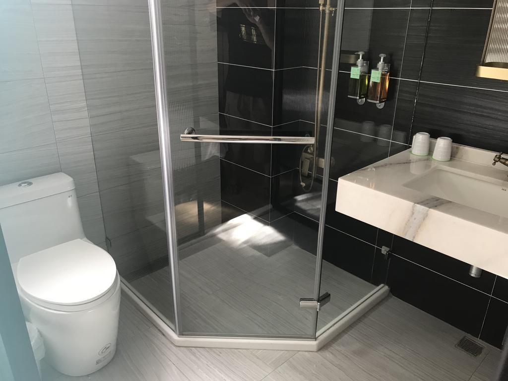 A modern bathroom with a glass-enclosed shower, a white toilet, and a vanity with a sink and mirror.