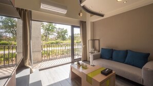 Un soggiorno moderno con un divano, un tavolino e vista su un balcone con piante.