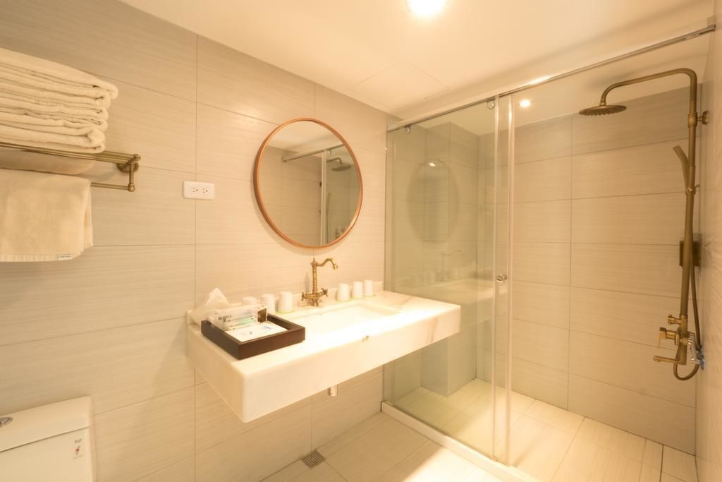 Un baño moderno con ducha de vidrio, lavamanos con espejo y toallas ordenadas.
