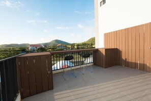 Una terraza con un cerramiento de madera, dos sillas negras y vistas a un paisaje montañoso.