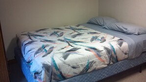 A single bed with a patterned bedspread and pillows, a quilted mattress, and a plain wall. - Waterfront 2 b.r. Bay View Cottage/sunsets/wineries/lighthouses/beaches/fishing (Sturgeon Bay)